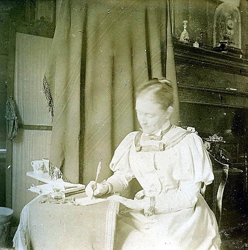 Black and white photo of Helen Ridgely writing at a desk.