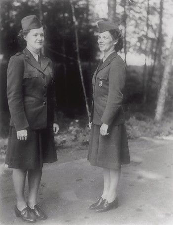Two women stand on a dirt path showing the new women's NPS uniform.