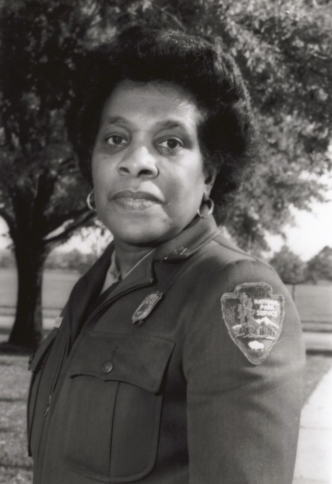 Georgia Ellard posing in her NPS uniform with a tree behind her.