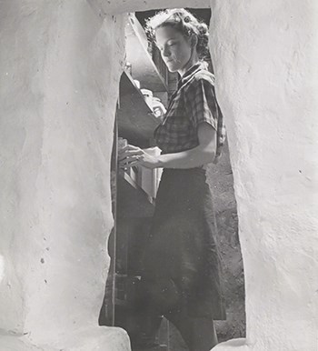 A woman is seen looking through the items on her pantry shelf.