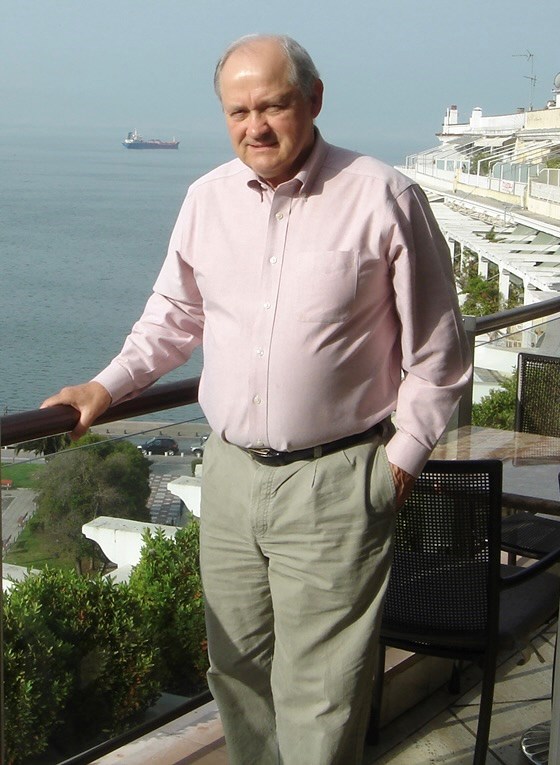 Ian Brown standing next to a railing in front of a seascape.