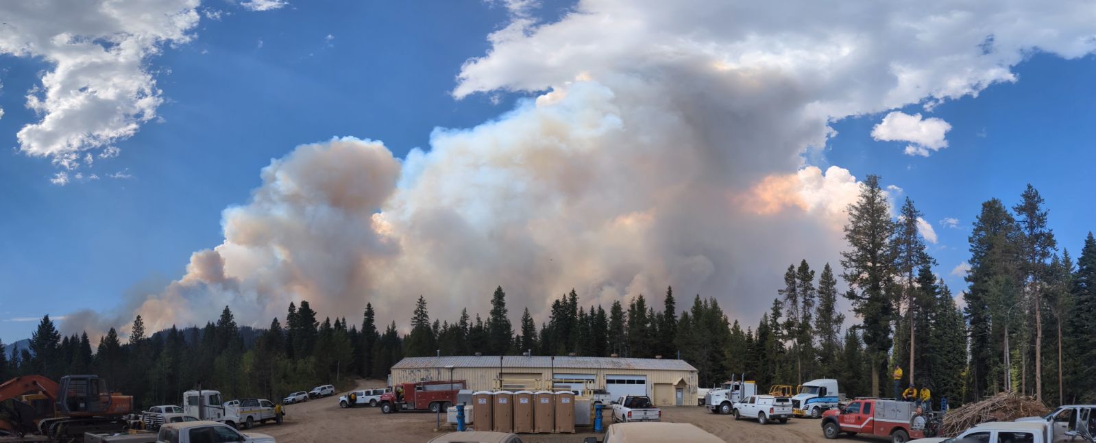 Billowing smoke covers the blue sky over several builings