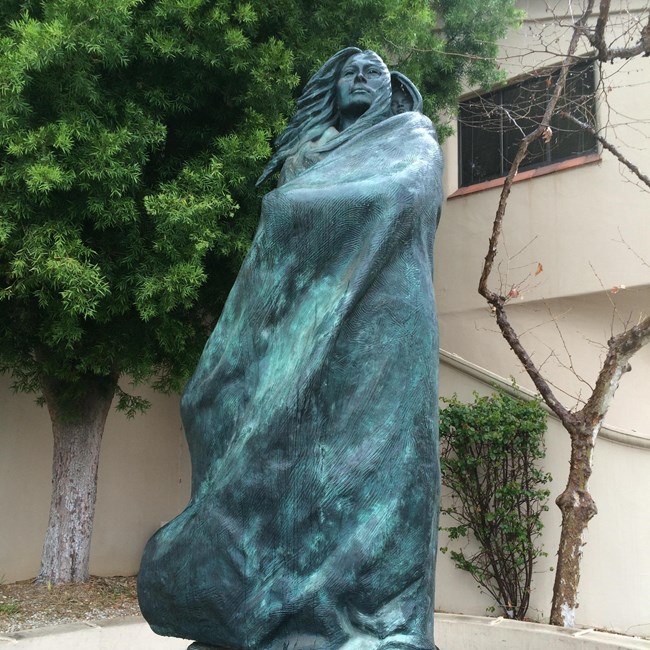 A statue of a native woman holding a baby on her back