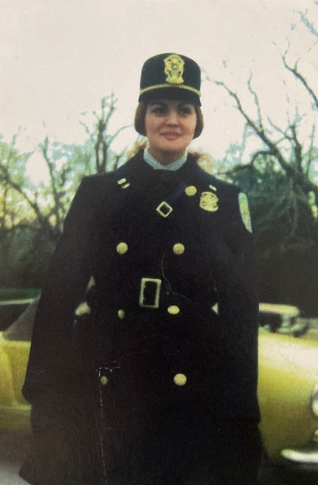Judy Schuster posing in her blue winter uniform coat and hat.