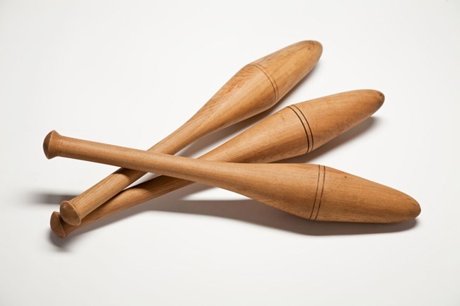 Three wooden juggling pins, with skinny base to hold them and a wider top