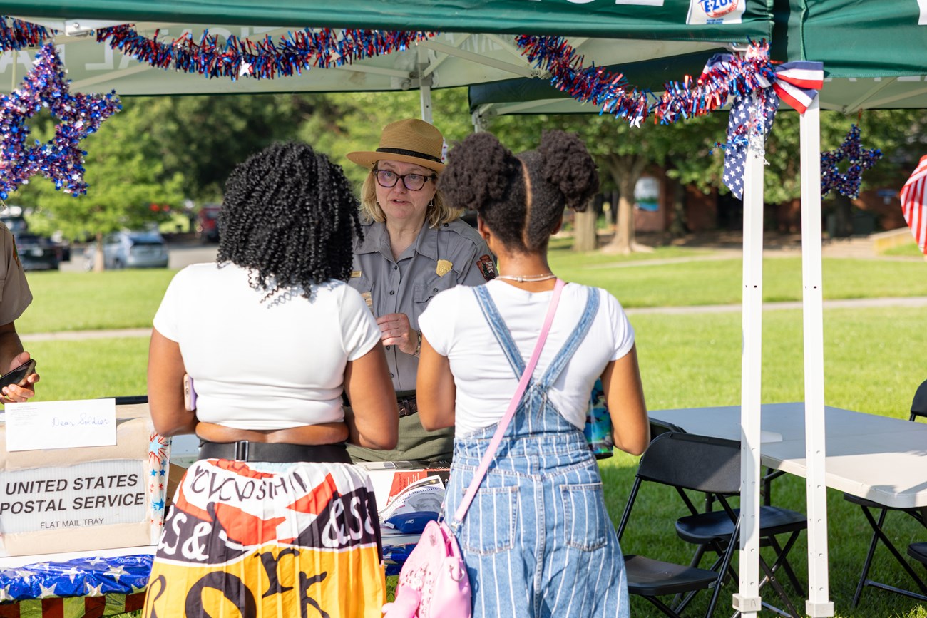 National Park Service Special Events Manager Julie Kutruff chats with two girls about writing thank-you letters to servicemembers and veterans during Late Skate at Anacostia Park Skating Pavilion in Washington, D.C., on June 28, 2025.