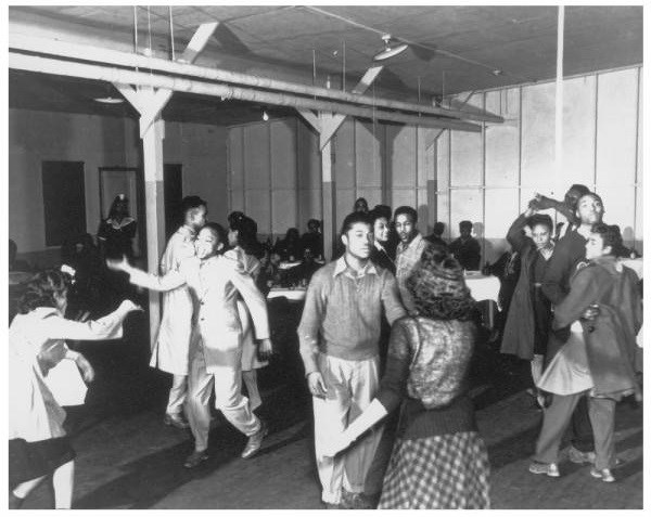 A group of African American teenagers dance inside a building.