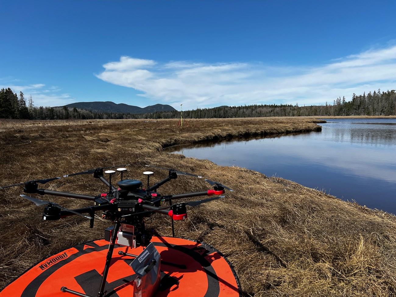 Outdoor photo of a marsh area with a research drone resting on the ground in the foreground