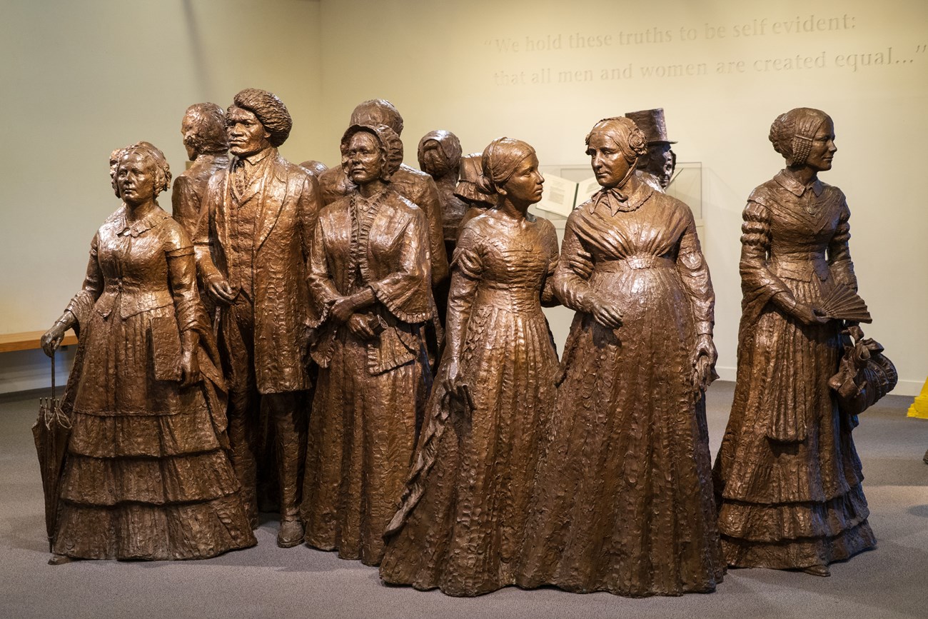 A group of bronze statues of men and women wearing nineteenth-century clothing.