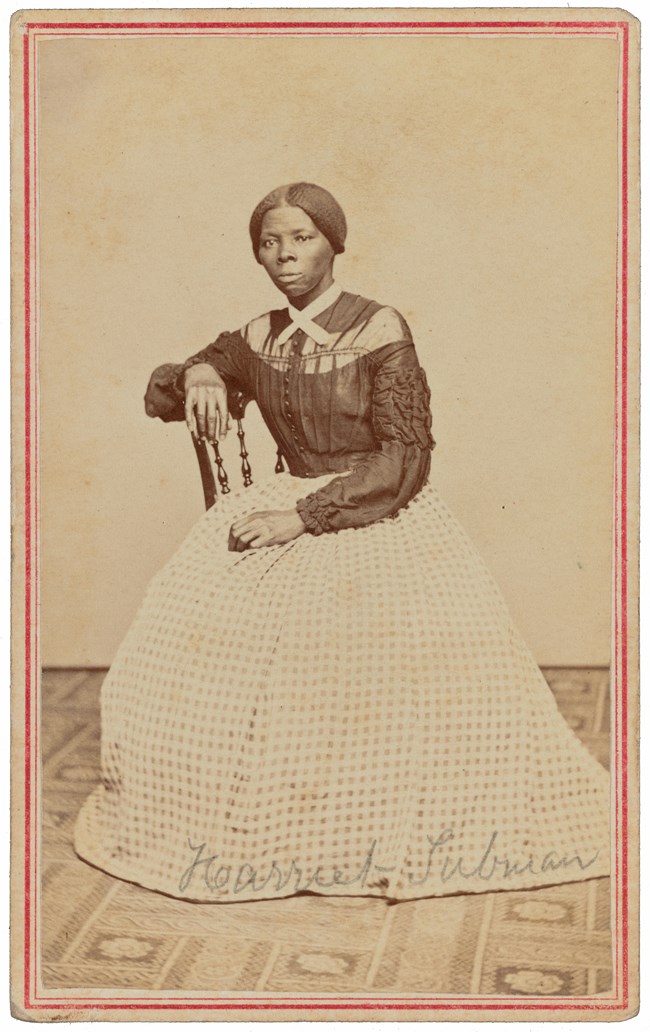 Harriet Tubman sitting in a chair in full length dress