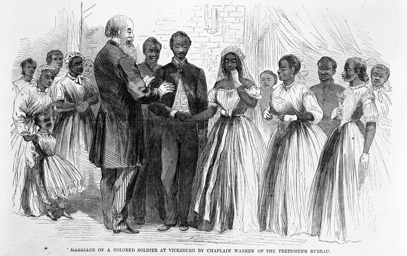 A group of people watch a wedding ceremony between a soldier and his finance.