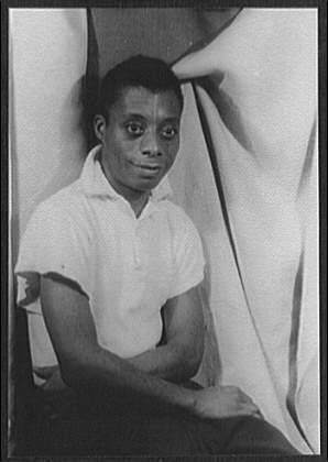 James Baldwin sits in a white shirt.