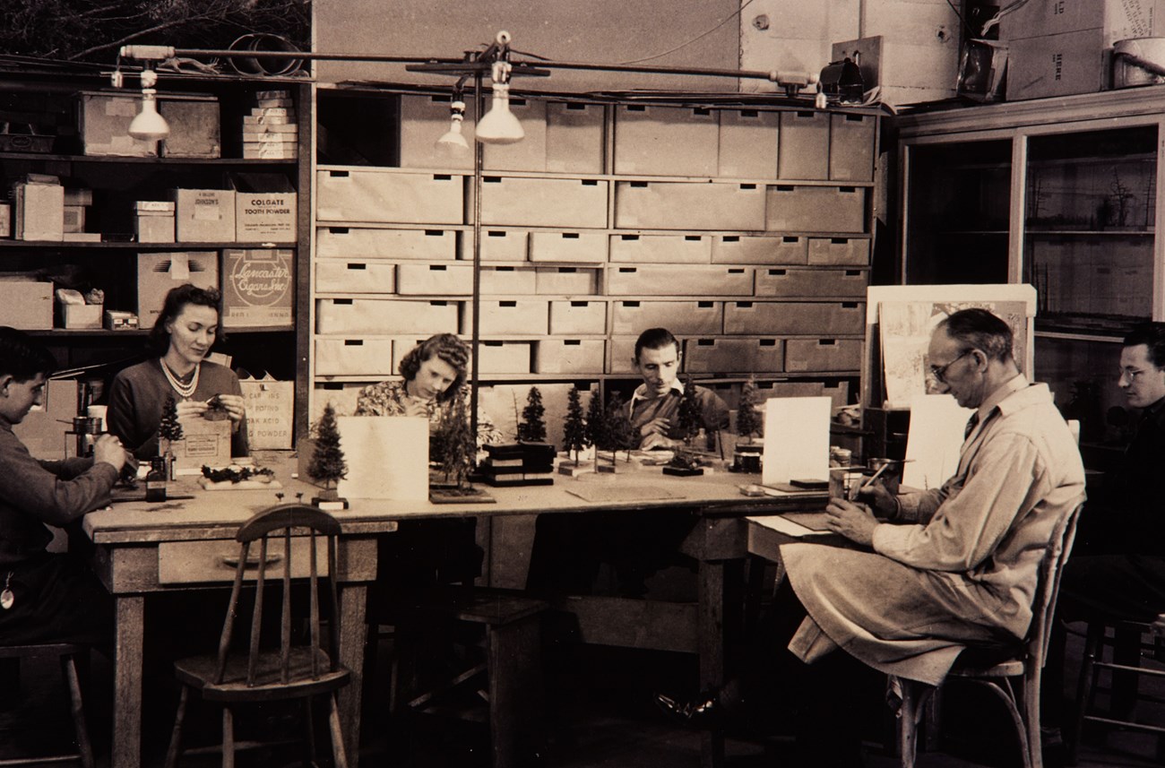 Men and women around a table making trees and other objects