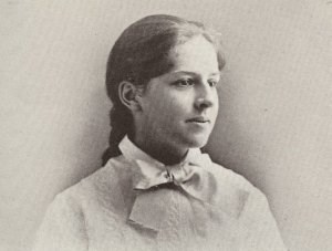 a teenage girl who is wearing a dress and also her brown hair is in a braid behind her