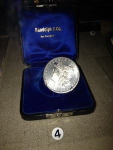 a silver coin displayed in a blue velvet case the size of a ring box