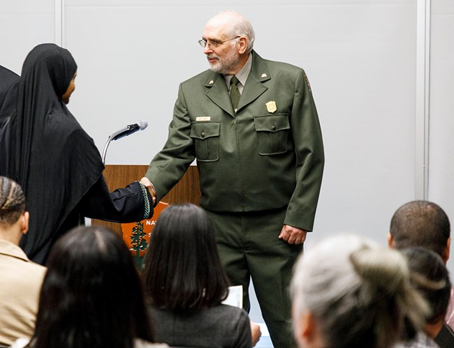 Regional director Bert Frost (right) shakes the hand of a young woman in a black abaya.