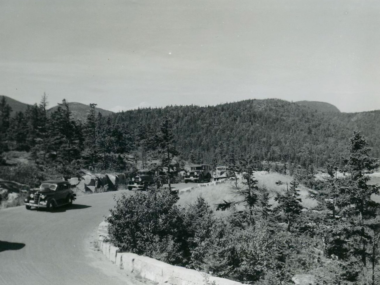 BW photo of old cars on a curved road