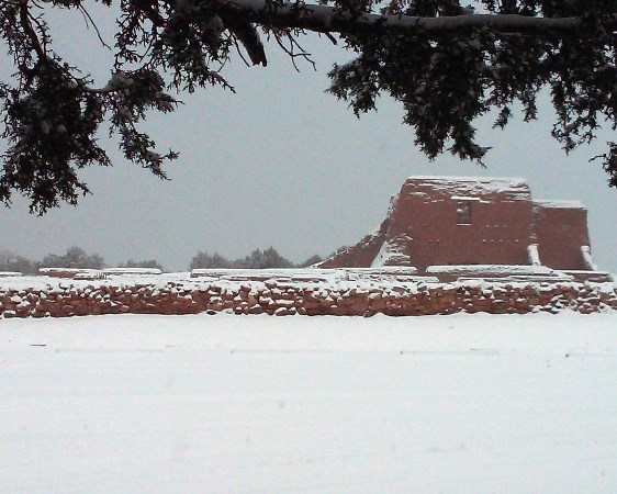 snow covered field, rock wall, and mission church ruins