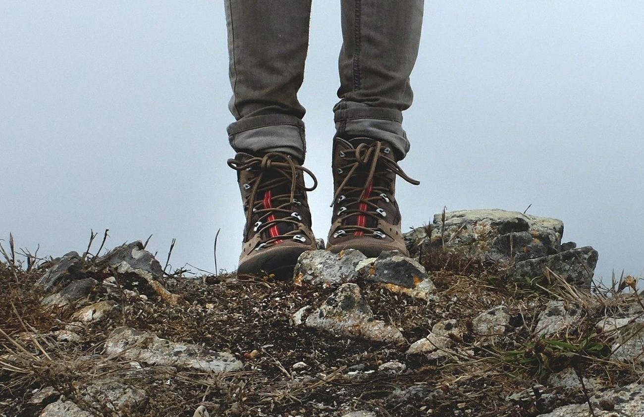 a close up image of a person's waterproof boots on rocky ground