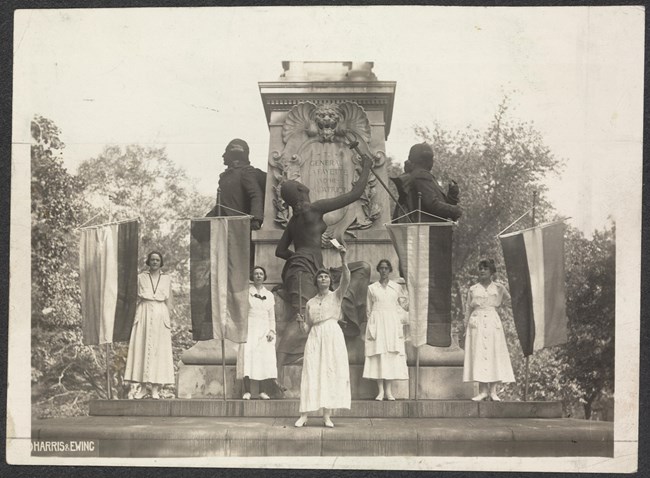 women stand in front of a statue of general lafayette