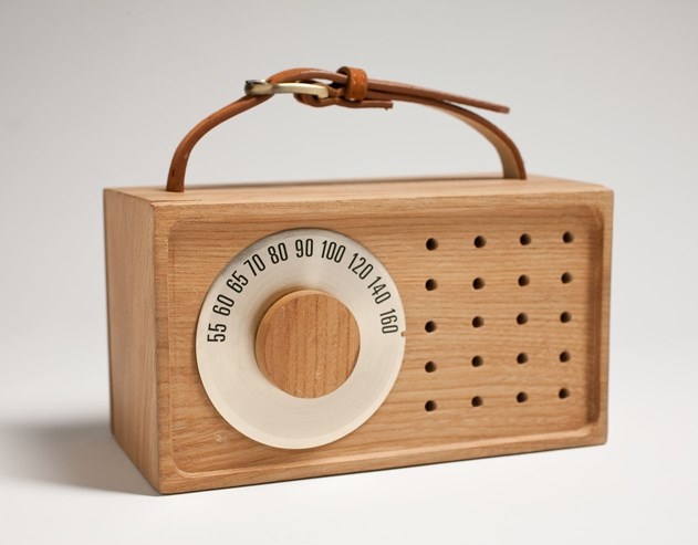 Wooden box radio, with leather strap at top to hold, hallow small circles, and a knob that can be adjusted to different numbers