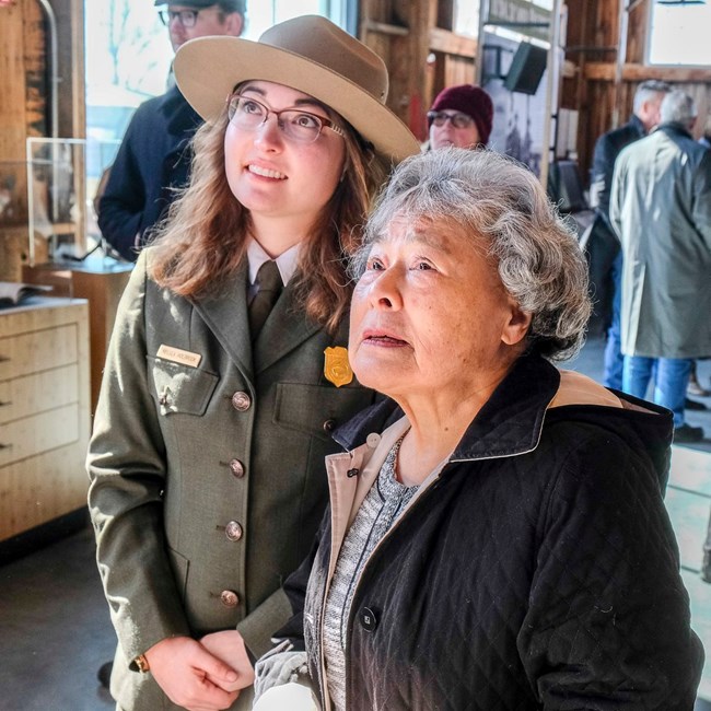 A ranger and an elderly woman look at exhibits.
