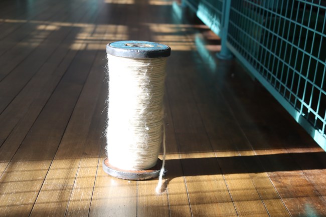 A large roll of thick yarn like cotton material placed on a wooden floor