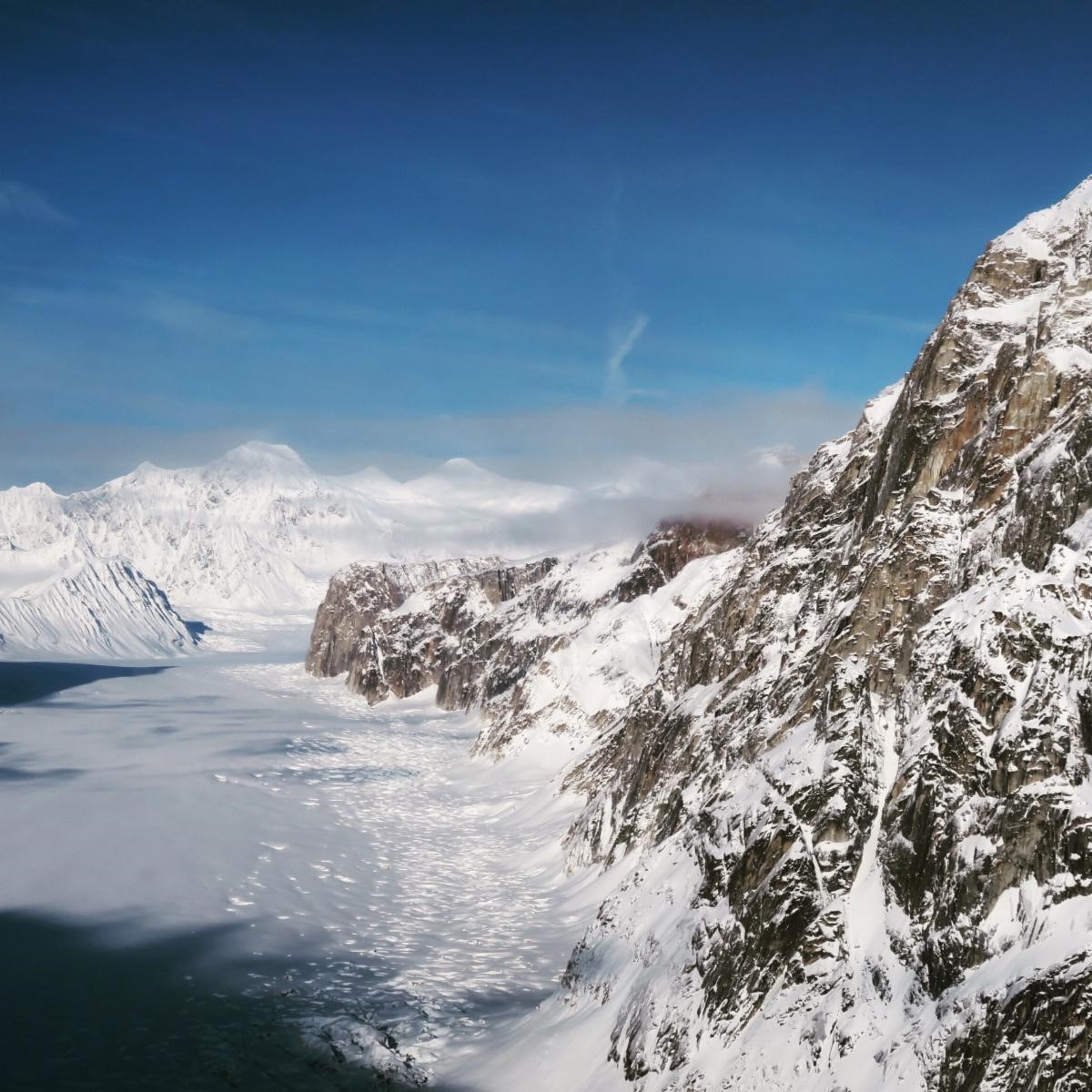 aerial view of craggy mountains looming over a vast white glacier