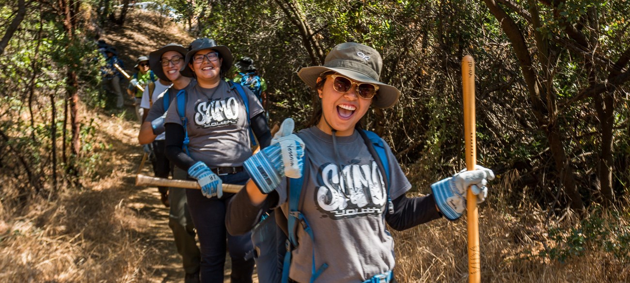 3 members of SAMO Youth volunteers giving a thumbs-up on a trail