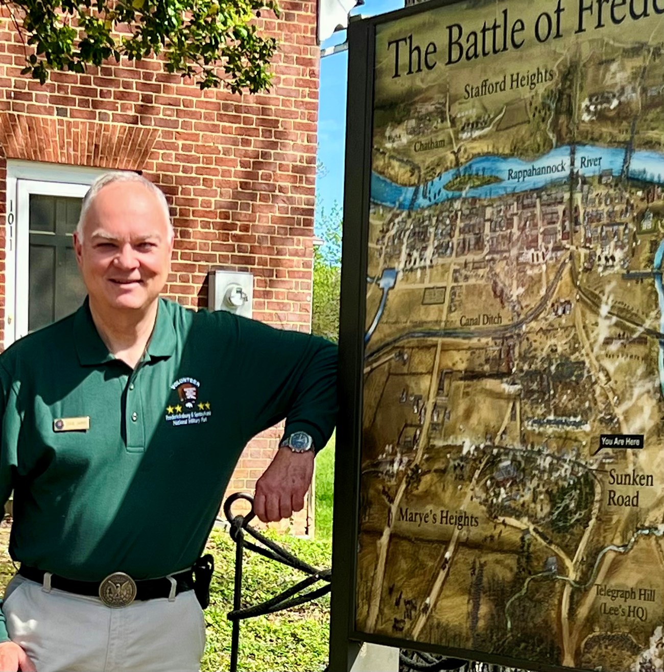 Fredericksburg and Spotsylvania National Military Park volunteer poses next to the outdoor battle map of the Battle of Fredericksburg.