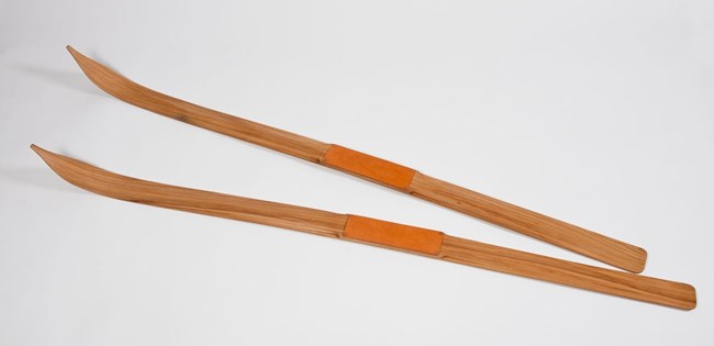 A pair of thin wooden skis, with triangular point at the top