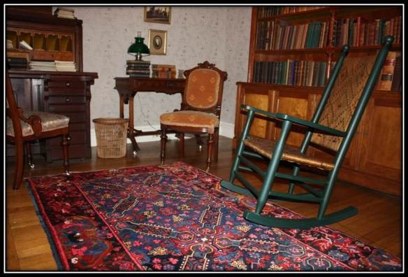 a room with 2 bookcases on the walls and 2 wicker sitting chairs