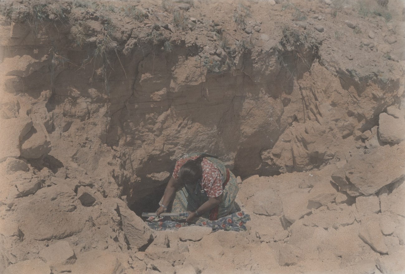 Legoria Tafoya digs clay out of the ground.
