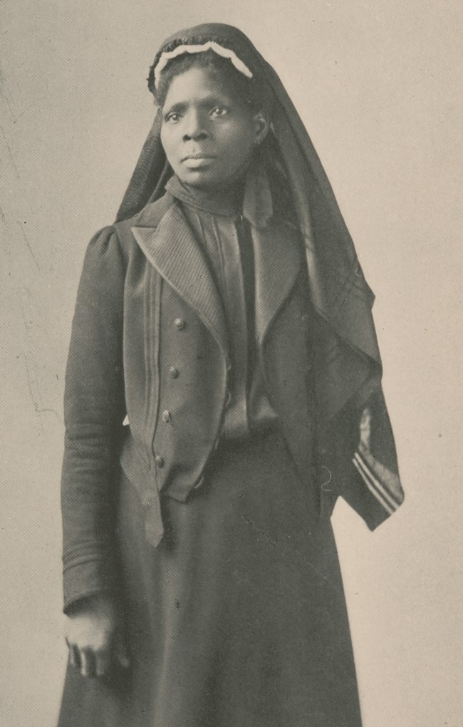 Black and white image of a black woman in a black dress.