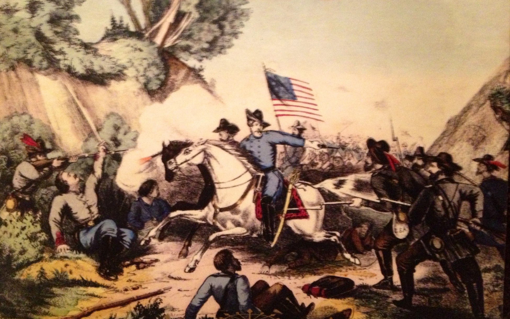 Historic illustration of frenzied battle. In foreground, man in blue uniform on white horse charges holding up American flag. He approaches two grey-uniformed men crouched by bushes at left, one holding sword and one aiming gun at other soldiers.