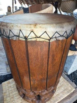 An unfinished carved temple drum sits next to a finished one.