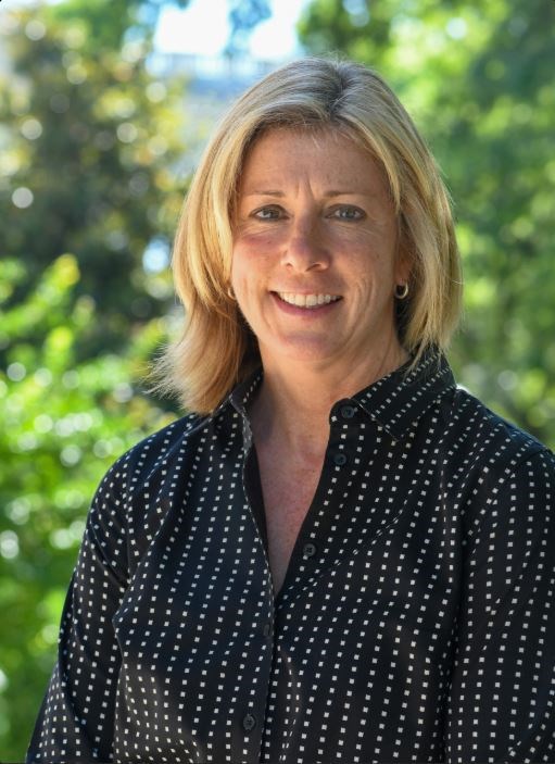 A blonde woman in a black shirt smiling for a portrait photo.