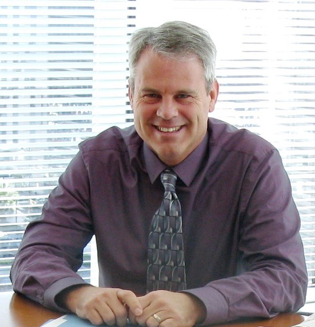 A man sitting at a table smiling at the camera.