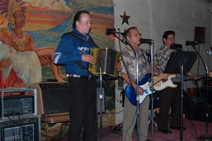 Three musicians on stage playing conjunto music