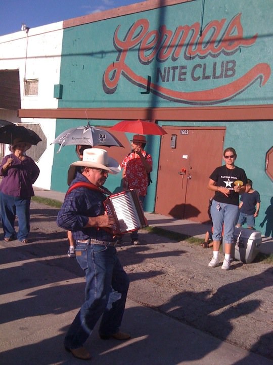 Musician with an accordion in front of a green building with orange letters