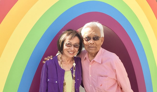 An elderly couple under a rainbow arch