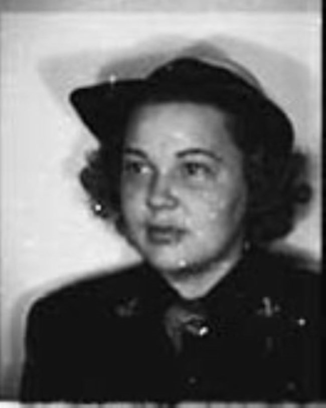 Black and white portrait of Sue Unger Eskey, a young woman with dark curly hair. She is wearing a hat with a brim and a dark blouse. She looks to the right of the camera with a neutral expression