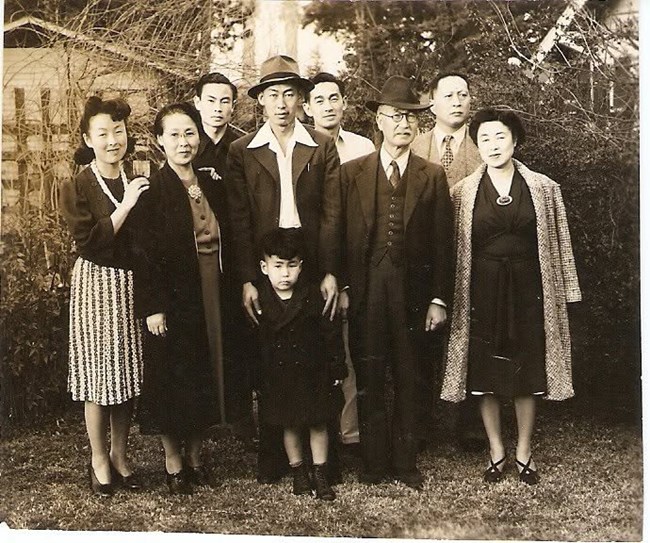 A group of eight standing for a photo in front of trees and bushes