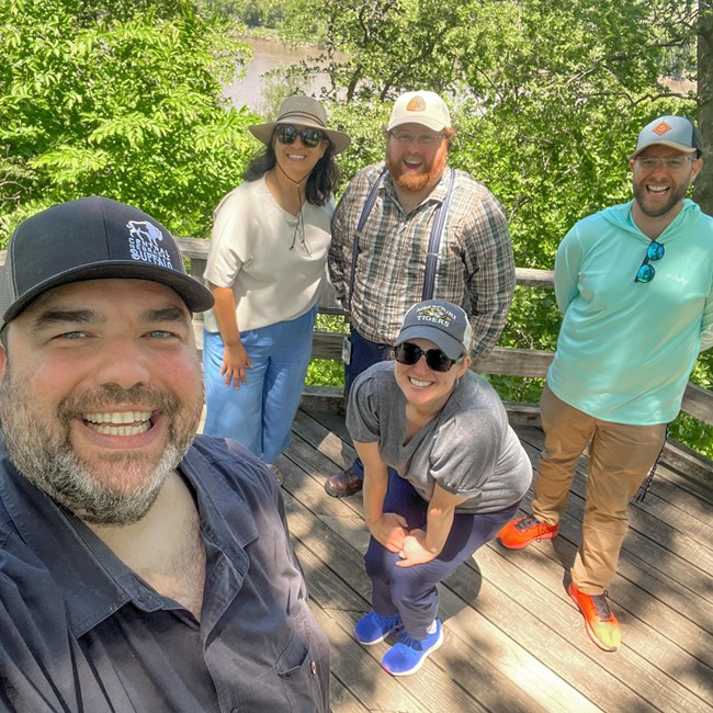 A group of five people wearing hats in a forest