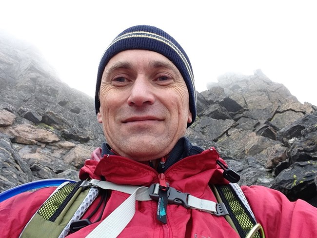 Selfie of person in outdoor gear amidst rocky terrain and fog