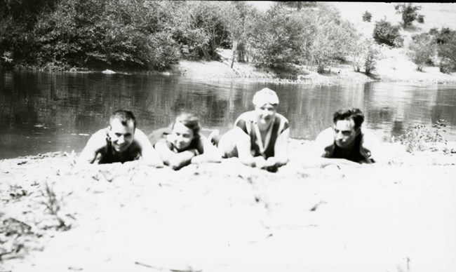 black and white photo of men and women playing in a lake