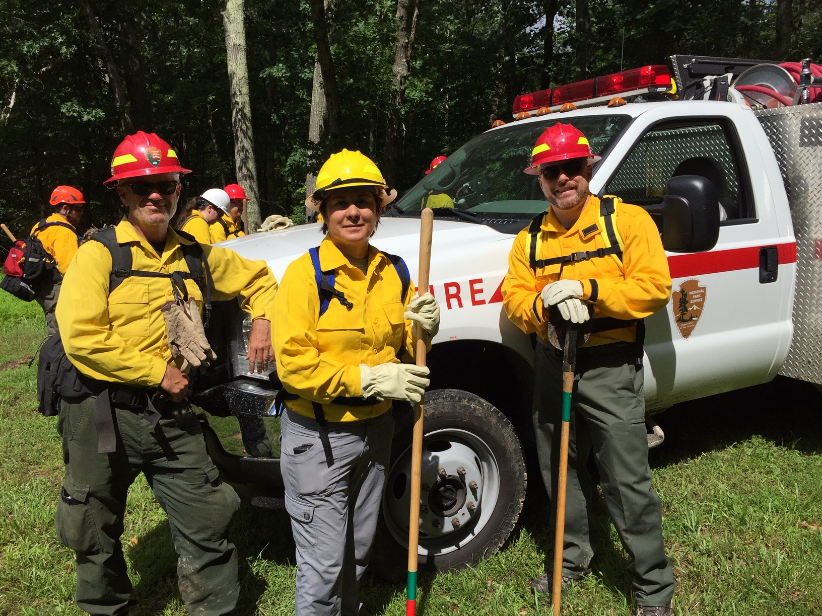Three wildland fire trainees in front of a fire engine