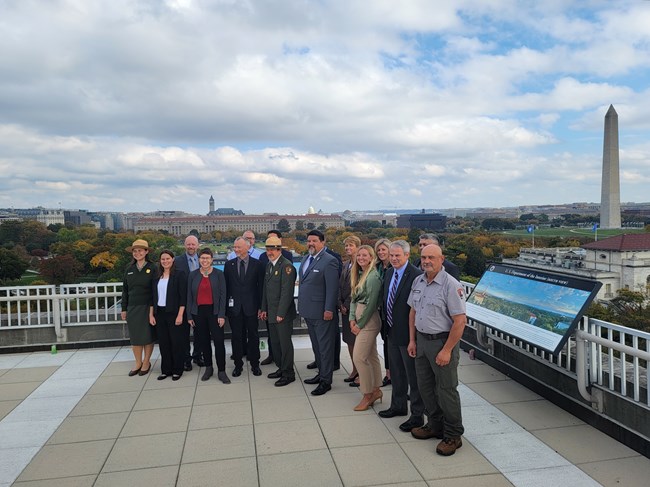 a group of people on a roof top, the Washington Monument in the background