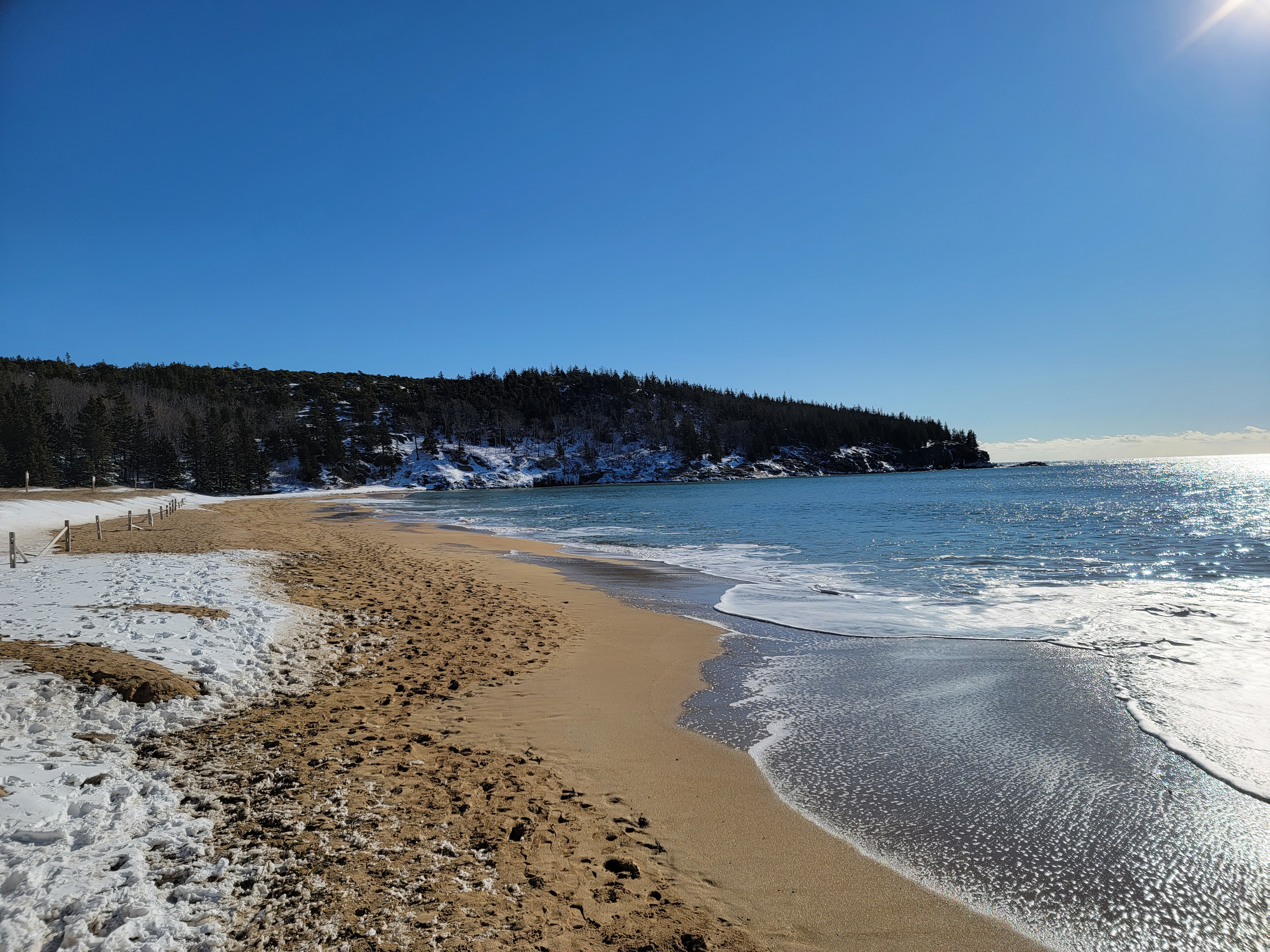 snow covers sand beach with ocean tide keeping some sand clear