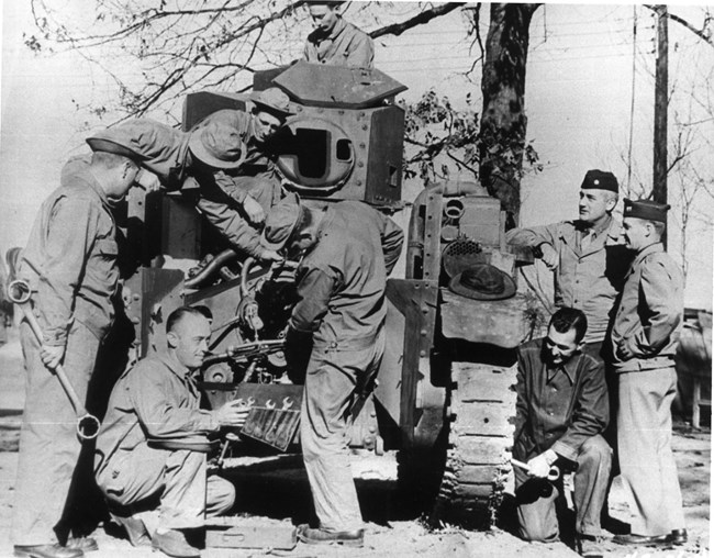 black and white photograph of a group of men repairing a tank